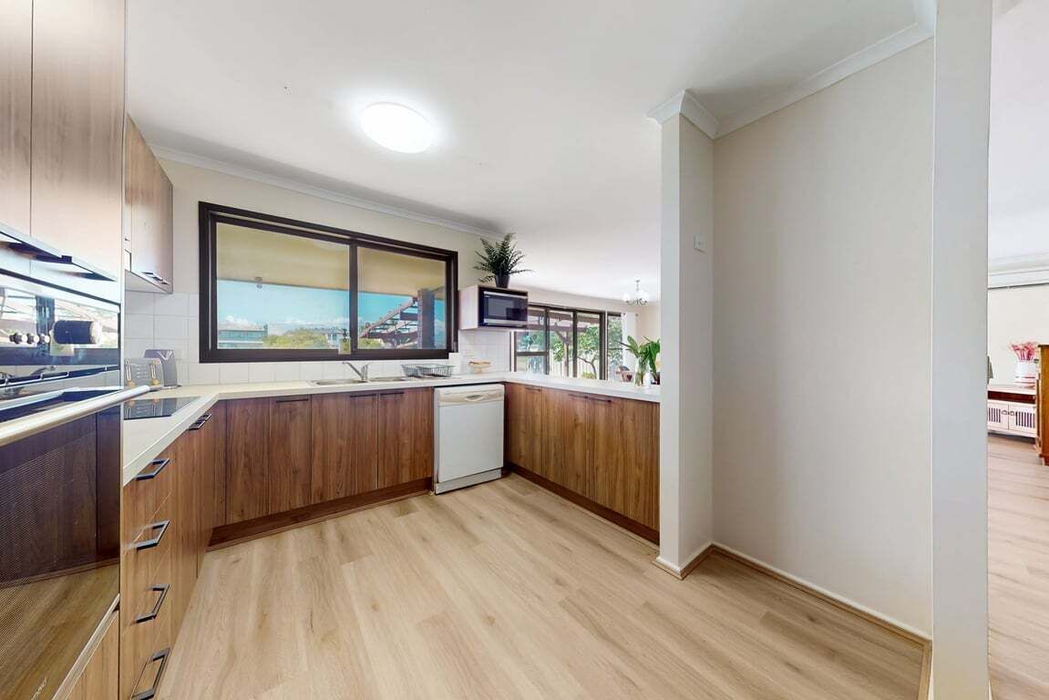 Una cocina moderna con armarios de madera, lavavajillas y un amplio ventanal con vistas panorámicas.