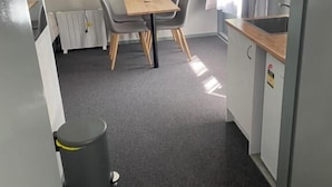 A compact room with a small dining table and chairs, a kitchenette, and a radiator. - Dawson Motel (Lismore)