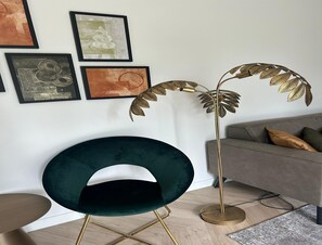 A modern living room with a dark green chair, a gold floor lamp, and a grey sofa with cushions. - Palette Resort De-steppe Family Stay (Ulicoten)