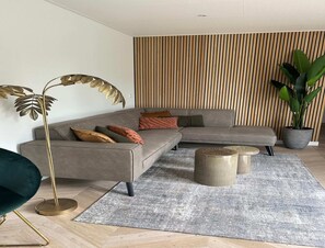Una sala de estar moderna con un sofá seccional, una lámpara de pie, una mesa de centro y una planta en maceta.