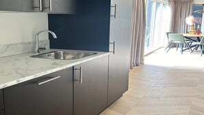 A modern kitchen with dark cabinets, a marble countertop, and a sink. - Palette Resort De-steppe Family Stay (Ulicoten)