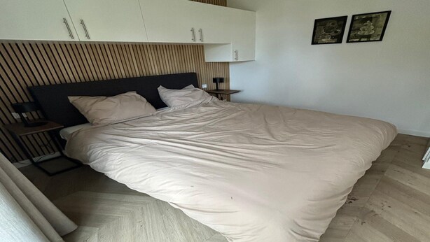 A modern bedroom with a bed, wooden slatted headboard, a nightstand, and two framed pictures on the wall. - Palette Resort De-steppe Family Stay (Ulicoten)