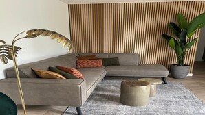 A modern living room with a sectional sofa, a floor lamp, a coffee table, and a large potted plant. - Palette Resort De-steppe Family Stay (Ulicoten)