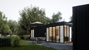 A modern outdoor dining area with a table and chairs, surrounded by a garden and a building with large glass doors. - Eco Forest Home by Palette Resort De-steppe (Ulicoten)