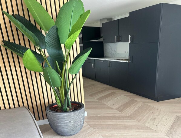 A modern kitchen with dark cabinets, a marble countertop, and a potted plant. - Eco Forest Home by Palette Resort De-steppe (Ulicoten)