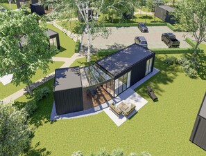 Ein modernes Haus mit großer Glasfassade, einer Terrasse mit Gartenmöbeln und einem gepflegten Rasen.