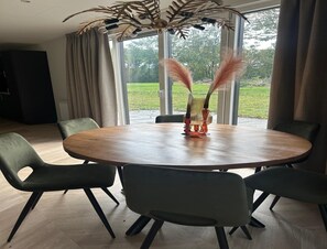 Ein Essbereich mit einem runden Holztisch, sechs Stühlen und einem dekorativen Mittelstück.