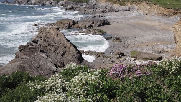A coastal landscape with rocky cliffs, waves crashing against the shore, and a grassy hill in the background. - Little Content Farm Cottage (Gunwalloe, near Helston)