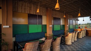 A restaurant with a checkered floor, green and blue seating areas, wicker chairs, and hanging light fixtures. - Pushkar Desert View (Pushkar)