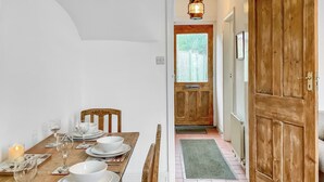 Ein Essbereich mit Holztisch, gedeckt für vier Personen, einer Kerze und Blick in einen Raum mit einer Holztür.