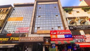 Un edificio de varios pisos que alberga diversos negocios, incluyendo una agencia de automóviles, un hotel y una inmobiliaria.