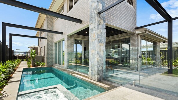 A modern house with a swimming pool, large glass doors, and a stone pillar.