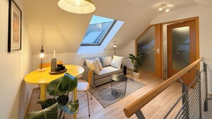 A modern loft bedroom with a skylight, a dining area with a yellow table, and a staircase. - Maisonette apartment, large groups, central - NEW (Erfurt)