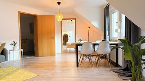A modern apartment with a dining area, kitchen, and a large window. - Maisonette apartment, large groups, central - NEW (Erfurt)