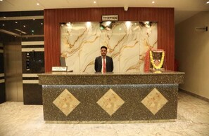 A reception desk with a marble design, a reception sign, and a garland decoration. - Hotel Sahil Suites (Katra)