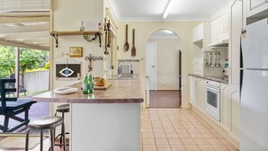 Een keuken met een centraal eiland, witte kasten en een eethoek met een tafel en stoelen.