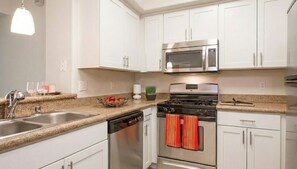 A modern kitchen with white cabinets, stainless steel appliances, granite countertops, and a dish drying rack. - Cozy 1-bedroom apartment in fabulous Marina del Rey with AC (Marina del Rey)