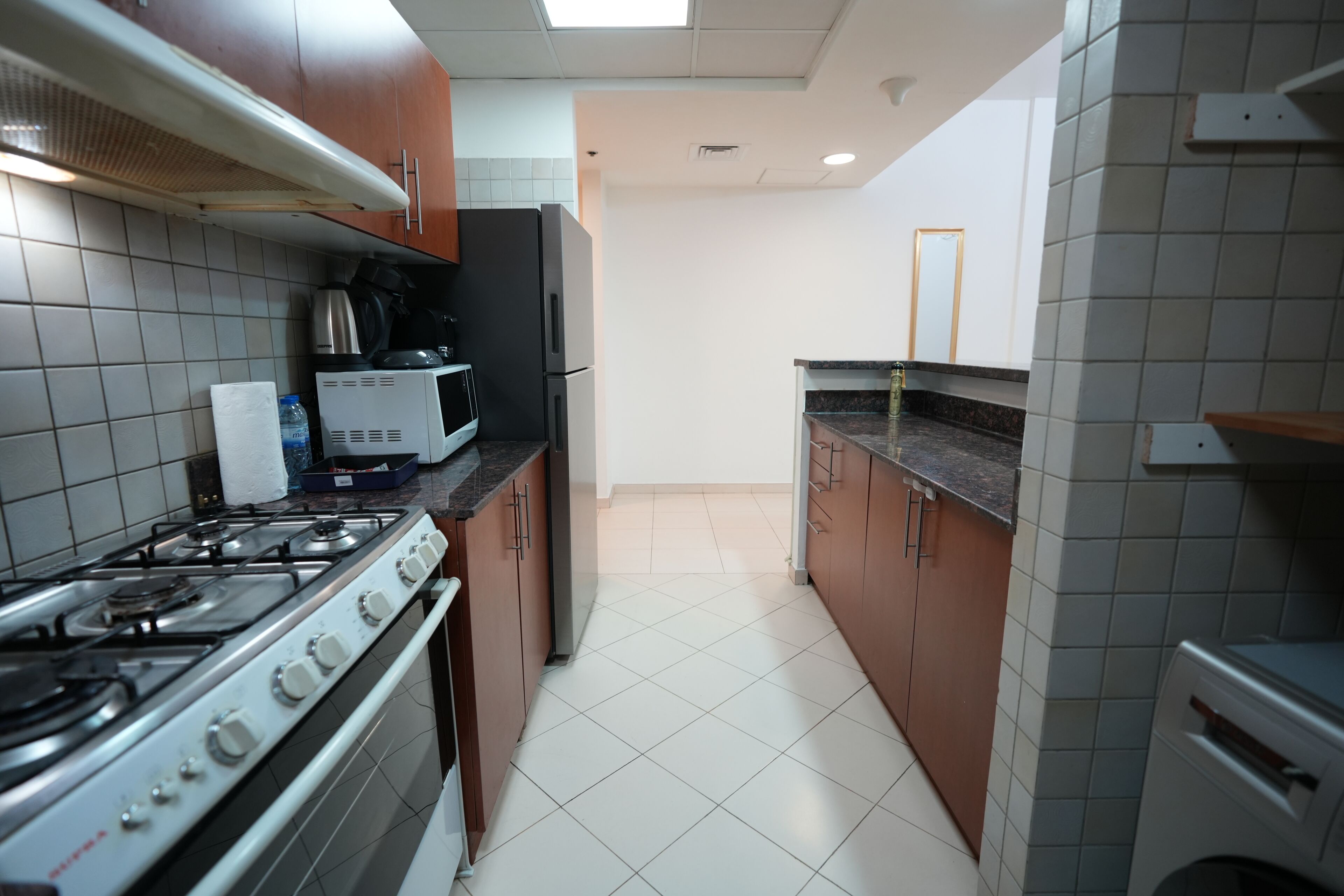 A kitchen with a gas stove, oven, microwave, and refrigerator.
