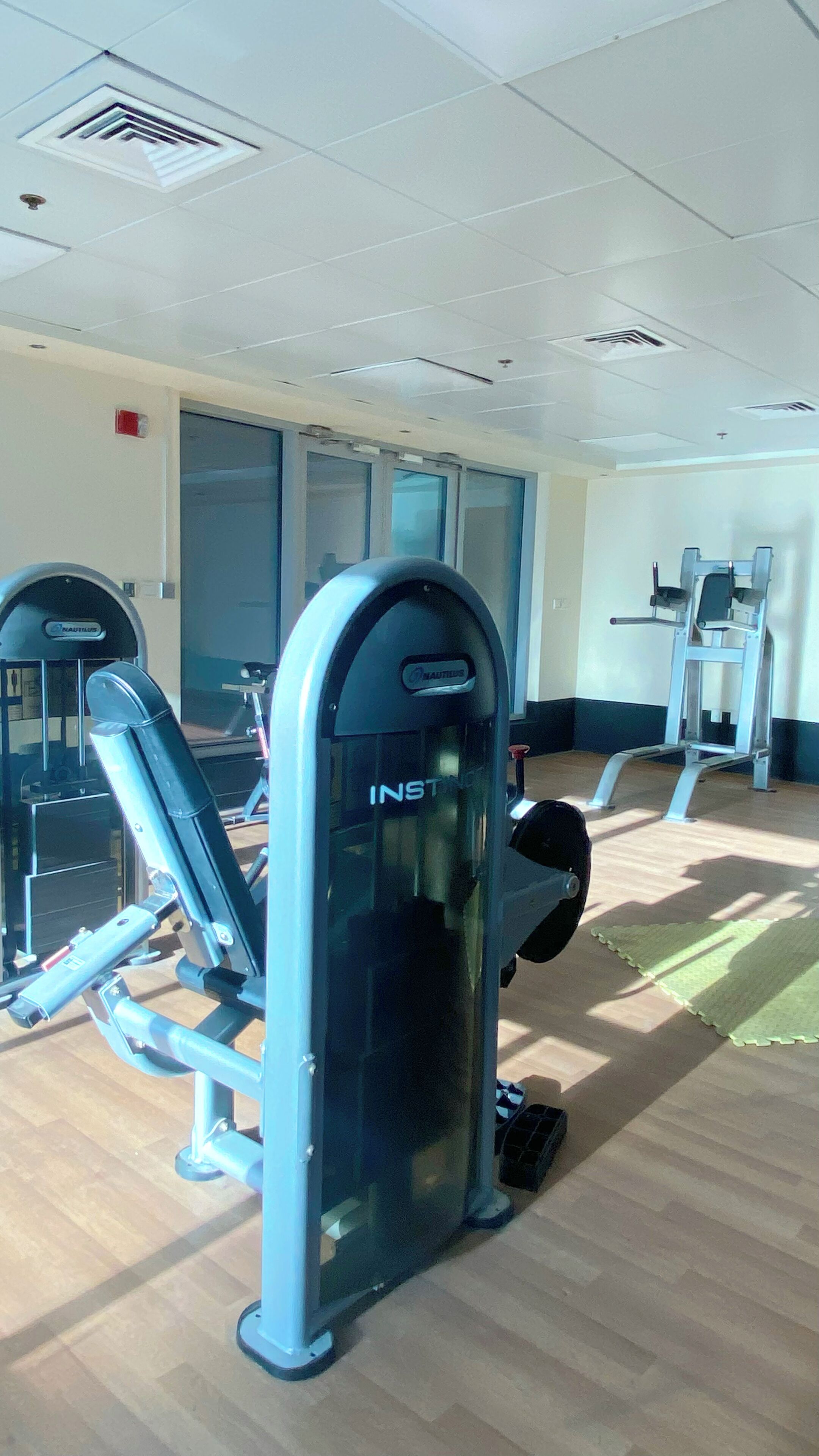 Ein Fitnessraum mit Nautilus- und INSTYLE-Trainingsgeräten, Holzboden und einem großen Spiegel.