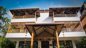 A two-story building with a central entrance, balconies on each floor, and a covered front porch. - ANANTYA AT ANAMIVA (Anjuna)