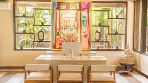 A room with a large window, a desk with a computer, three chairs, and a statue. - ANANTYA AT ANAMIVA (Anjuna)