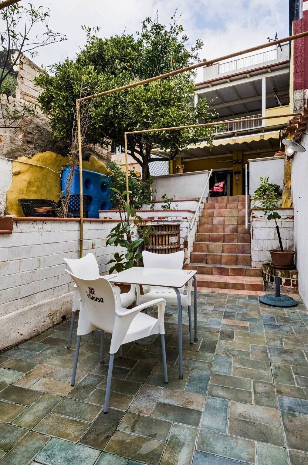 A patio with a table and chairs, a staircase, and a building in the background.