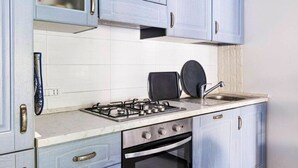 Eine Küche mit hellblauen Schränken, einem Gasherd, einem Backofen und einem Spülbecken.