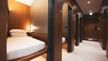 A hotel room with a bed, wooden walls, and a corridor with doors.