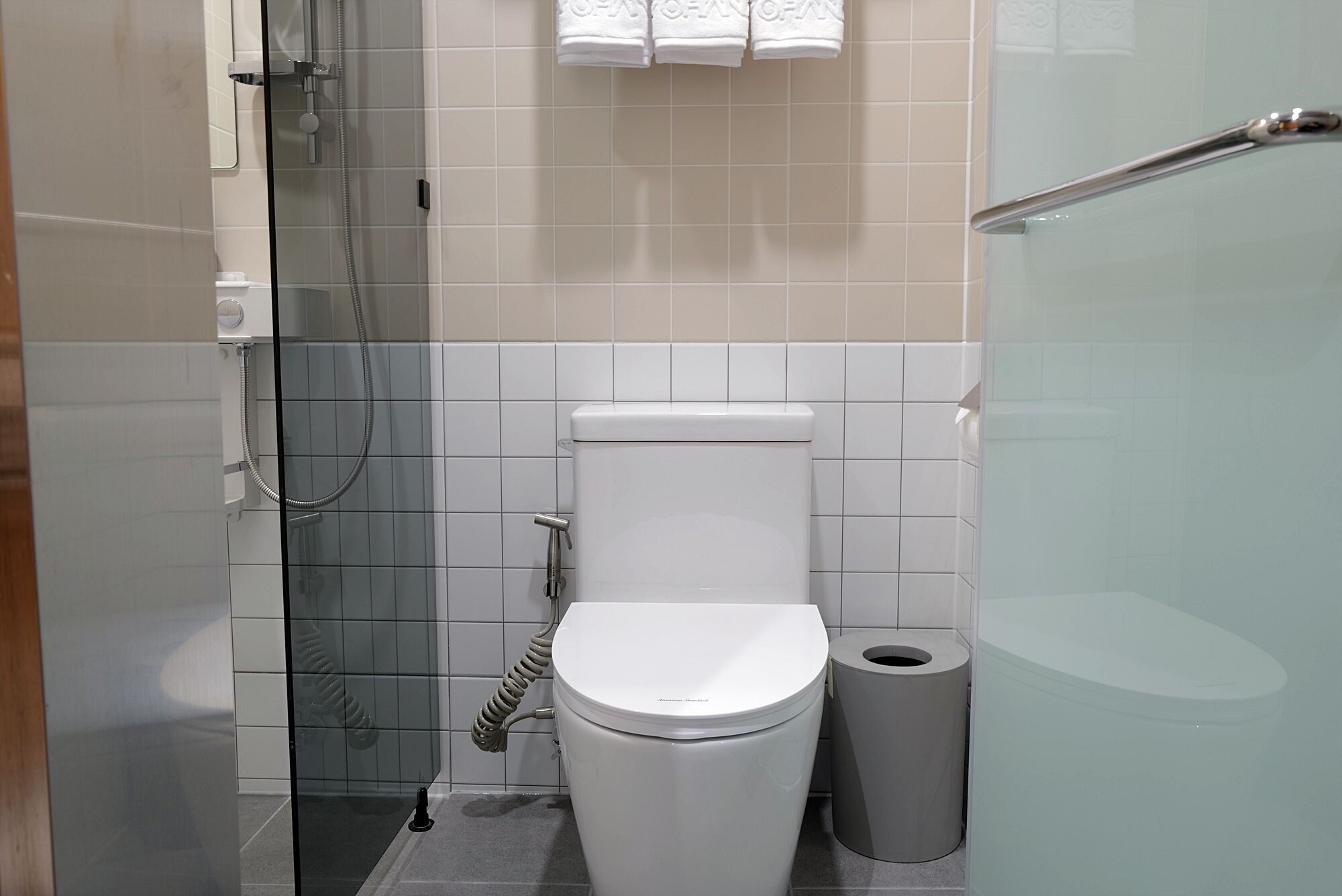 Une salle de bain moderne équipée de toilettes, d’une douche à parois de verre et d’une poubelle.