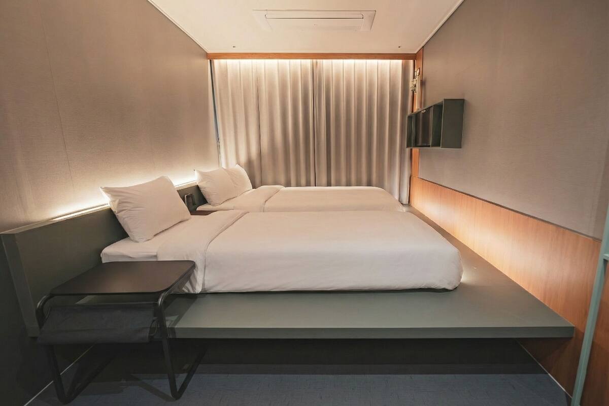 Una moderna camera d'albergo con un letto, comodini, televisione e tende.