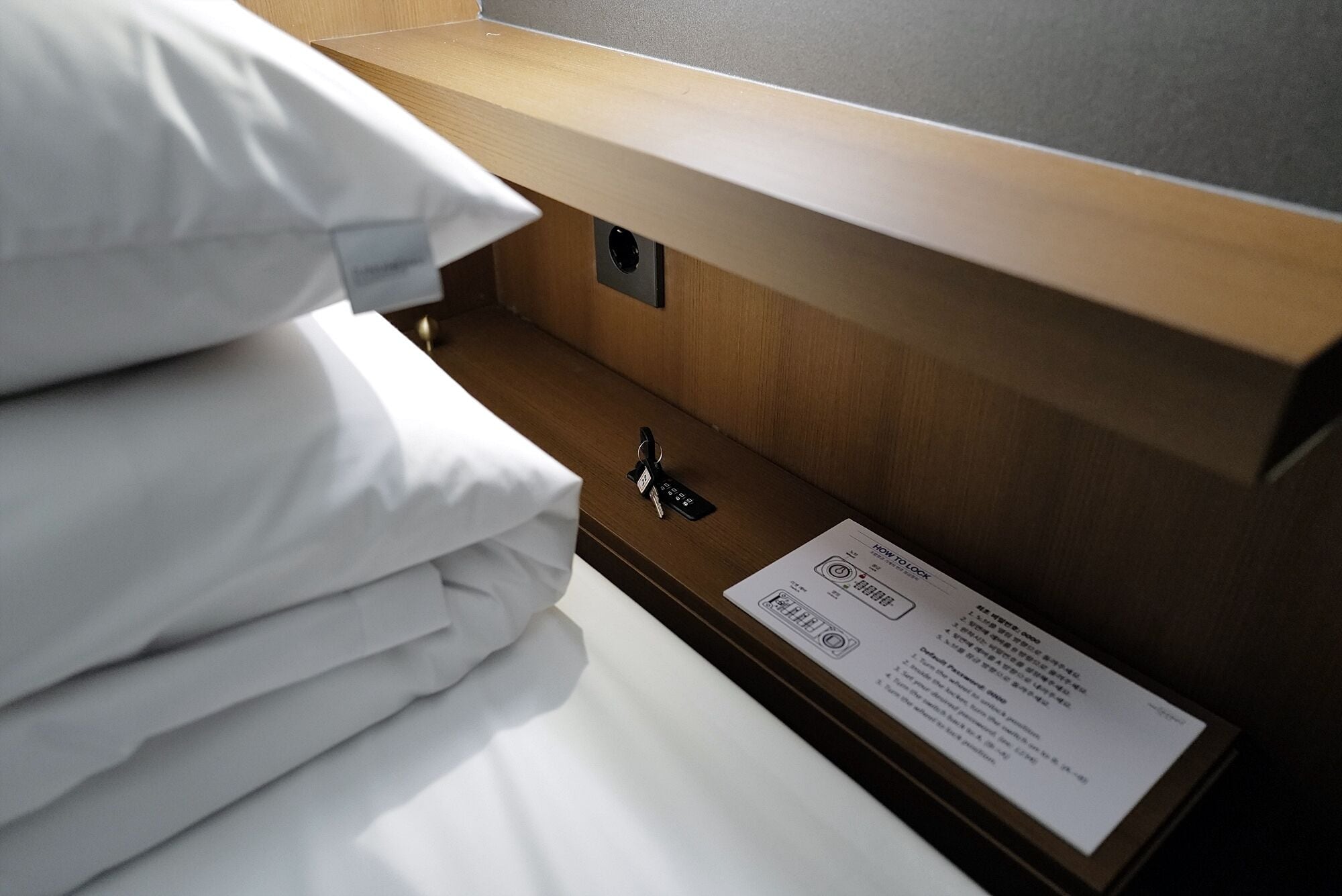 Una cama bien hecha con sábanas blancas, cabecera de madera y un llavero al lado.