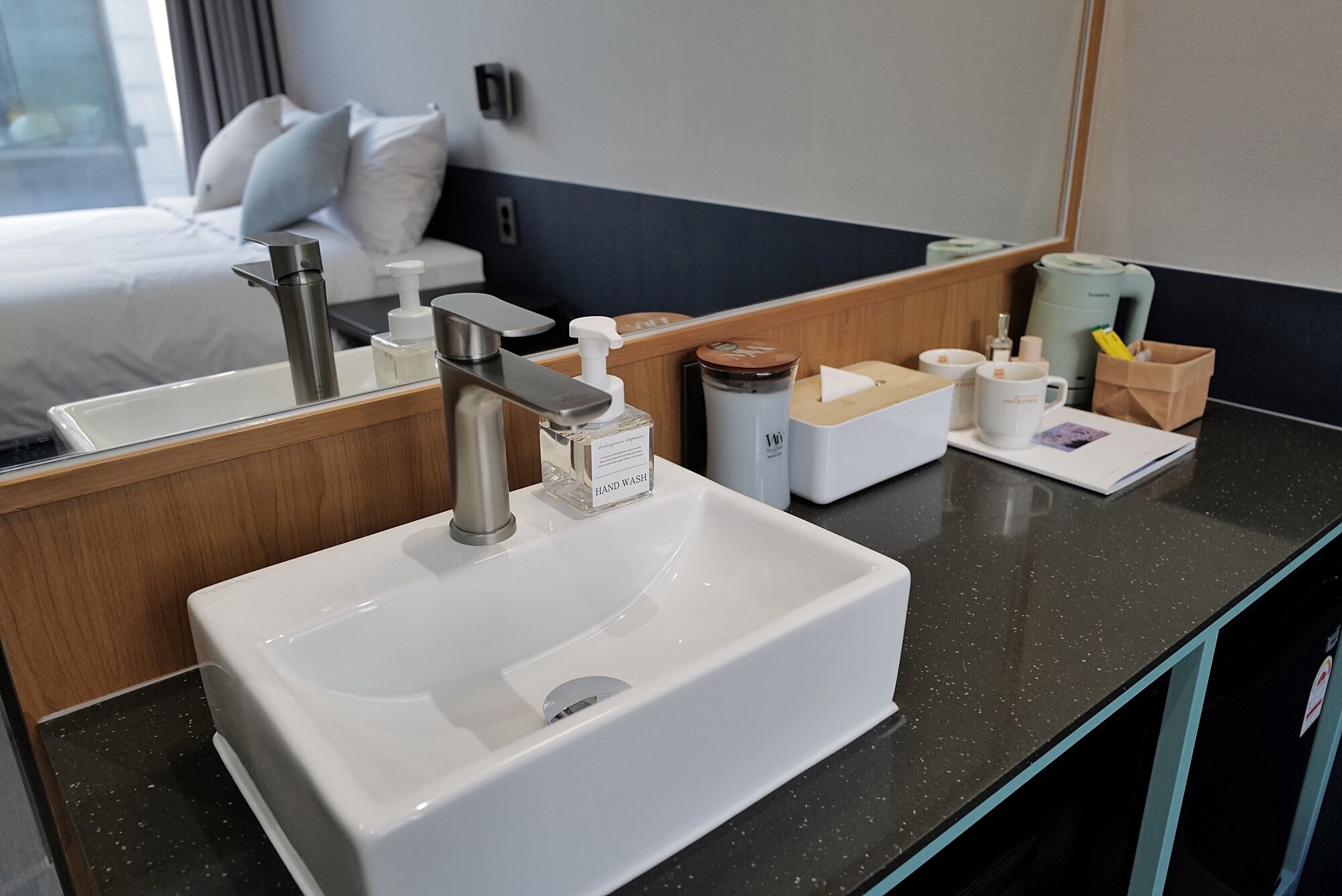 A hotel bathroom with a white sink, a modern faucet, and a mirror.