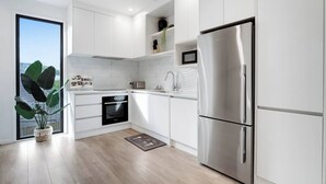 Eine moderne Küche mit weißen Schränken, einem Edelstahlkühlschrank und einem eingebauten Backofen.