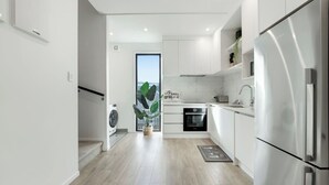 Eine moderne Küche mit weißen Schränken, Edelstahlgeräten und einem großen Fenster.