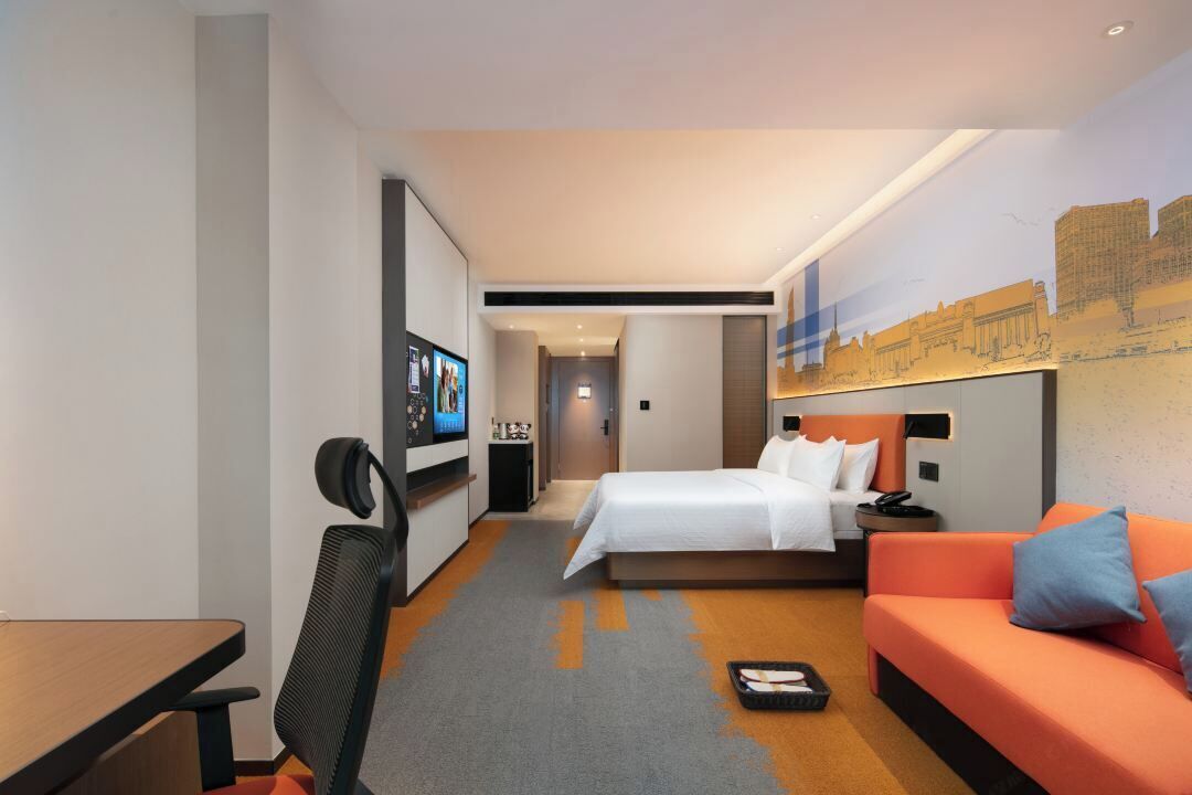 Habitació d'hotel amb llit, sofà, escriptori i televisió.