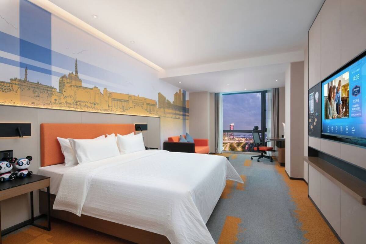 Hotelkamer met een groot bed, een stadsgezicht muurschildering, een televisie en uitzicht op de stad.