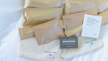 Variedad de productos para el cuidado de la piel y cabello en bolsas de papel marrón y una caja blanca sobre superficie blanca.