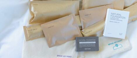Variedad de productos para el cuidado de la piel y cabello en bolsas de papel marrón y una caja blanca sobre superficie blanca.