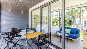 A modern outdoor living area with a wooden table, chairs, a grill, and a sofa with cushions. - SPACE KEY POINT RIVIERA ZUSHI MARINA (Zushi)