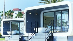Two modern, white, two-story buildings with large windows and balconies, surrounded by palm trees and a red-roofed building in the background. - SPACE KEY POINT RIVIERA ZUSHI MARINA (Zushi)