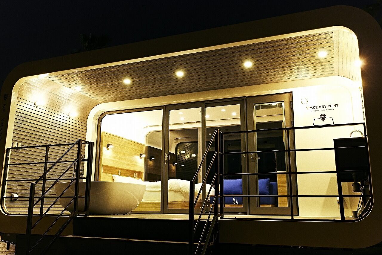 A modern, well-lit room with a large bed, a sink, and a staircase leading to another level.