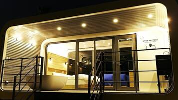 A modern, well-lit room with a large bed, a sink, and a staircase leading to another level.