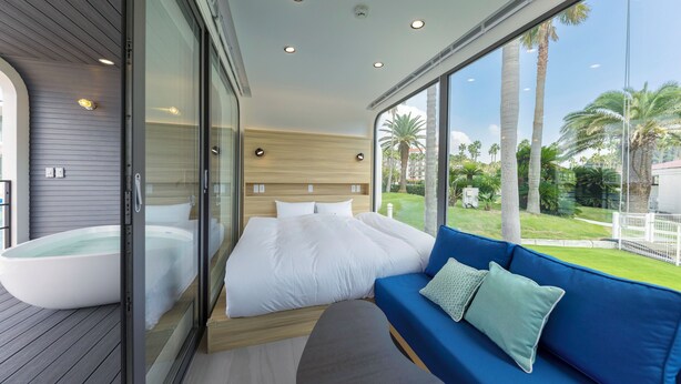 A modern bedroom with a large bed, a blue sofa, and a glass-enclosed jacuzzi. - SPACE KEY POINT RIVIERA ZUSHI MARINA (Zushi)
