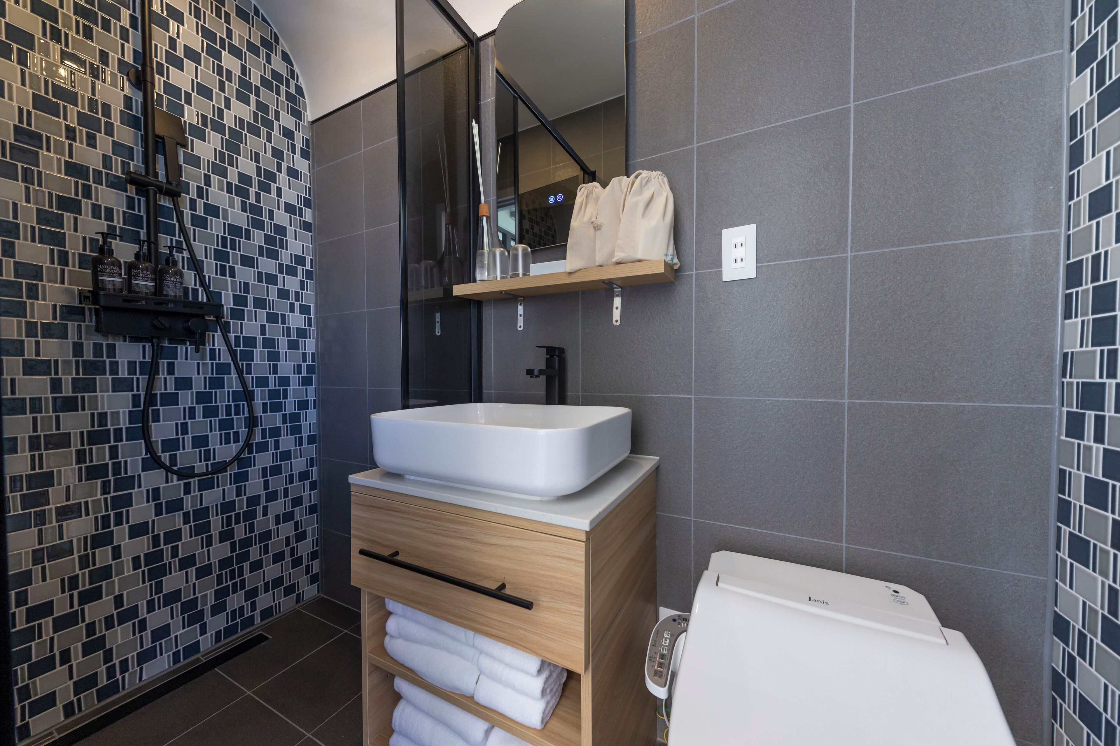 A modern bathroom with a large white sink, wooden vanity, and a toilet.