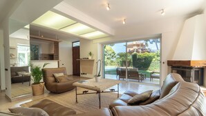 A spacious living room with a leather sofa, a coffee table, and a fireplace. There is a large sliding glass door leading to an outdoor patio. - 2BR Cozy Villa Saint-Jean-Cap-Ferrat (Saint-Jean-Cap-Ferrat)