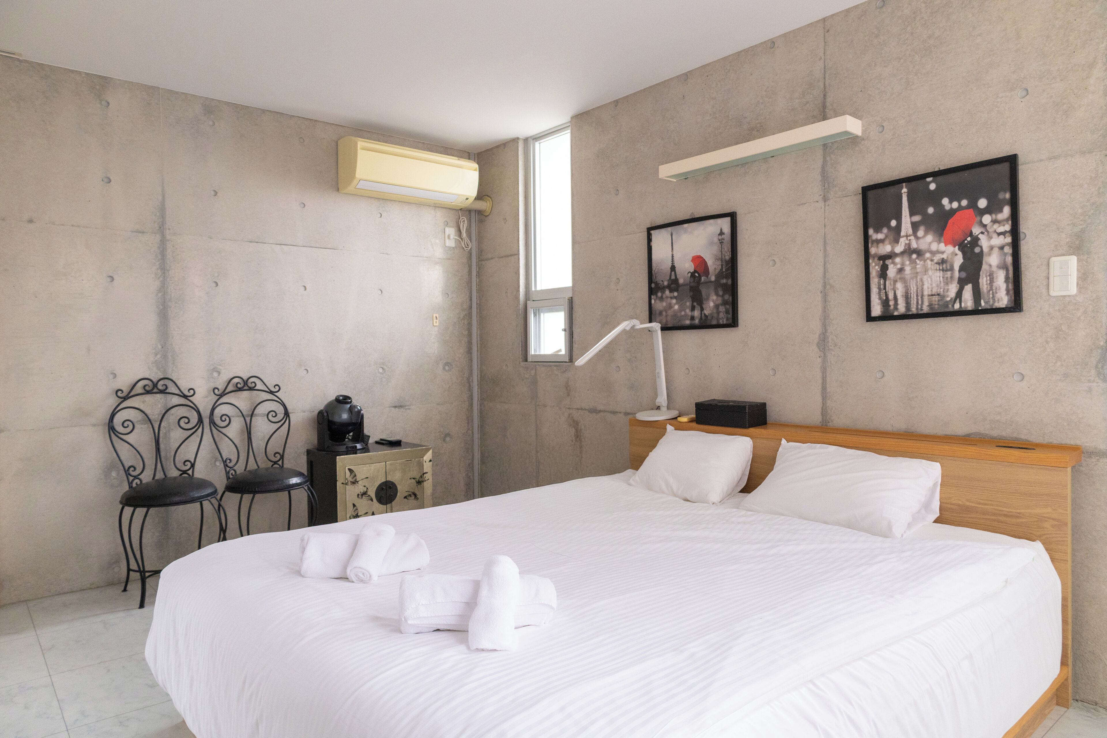 Un dormitorio moderno con una cama grande, una mesita de noche, una lámpara y dos sillas.