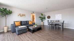 A modern living room with a sofa, coffee table, and dining area. - Spacious 2BR +Rooftop Pool+ view of Hollywood Sign (Los Angeles)