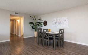 A dining area with a table and chairs, a potted plant, and a wall-mounted artwork. - Spacious 2BR +Rooftop Pool+ view of Hollywood Sign (Los Angeles)