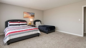 A bedroom with a large bed, a smaller bed, a nightstand with a lamp, and a painting on the wall. - Spacious 2BR +Rooftop Pool+ view of Hollywood Sign (Los Angeles)