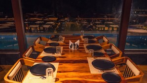Mesa de comedor dispuesta para ocho personas, con sillas, vista a una piscina y un balcón.